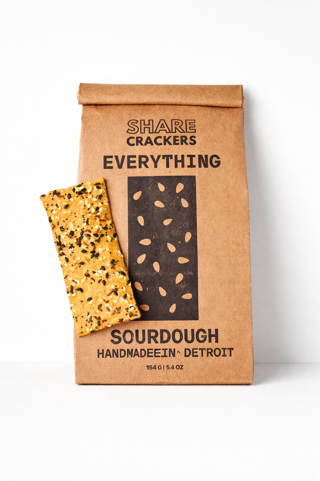 Brown paper bag of 'Share Crackers Everything' sourdough crackers on a white background