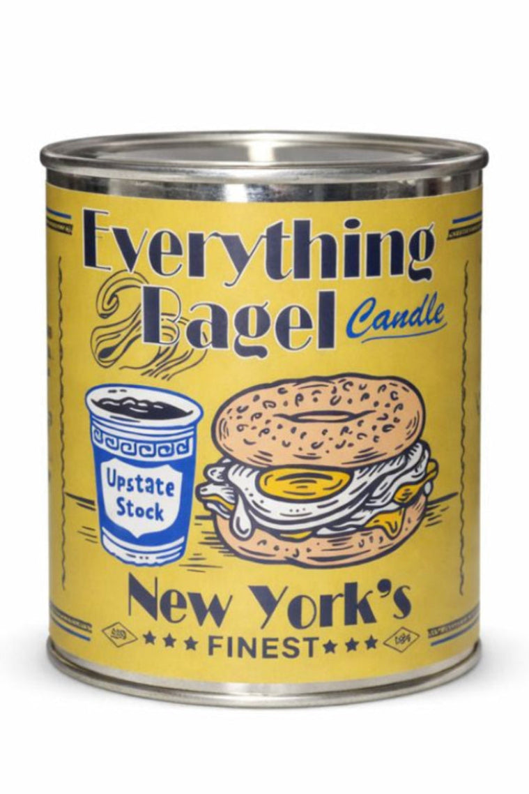 A yellow metal candle tin labeled 'Everything Bagel Candle' with an illustration of a bagel sandwich, upstate stock, and 'New York's Finest' text, photographed on a white background.