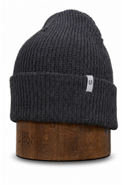 A dark charcoal gray ribbed knit beanie hat displayed on a brown wooden stand against a plain white background.
