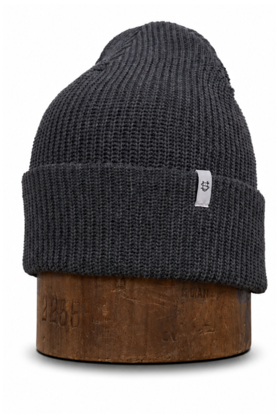 A dark charcoal gray ribbed knit beanie hat displayed on a brown wooden stand against a plain white background.