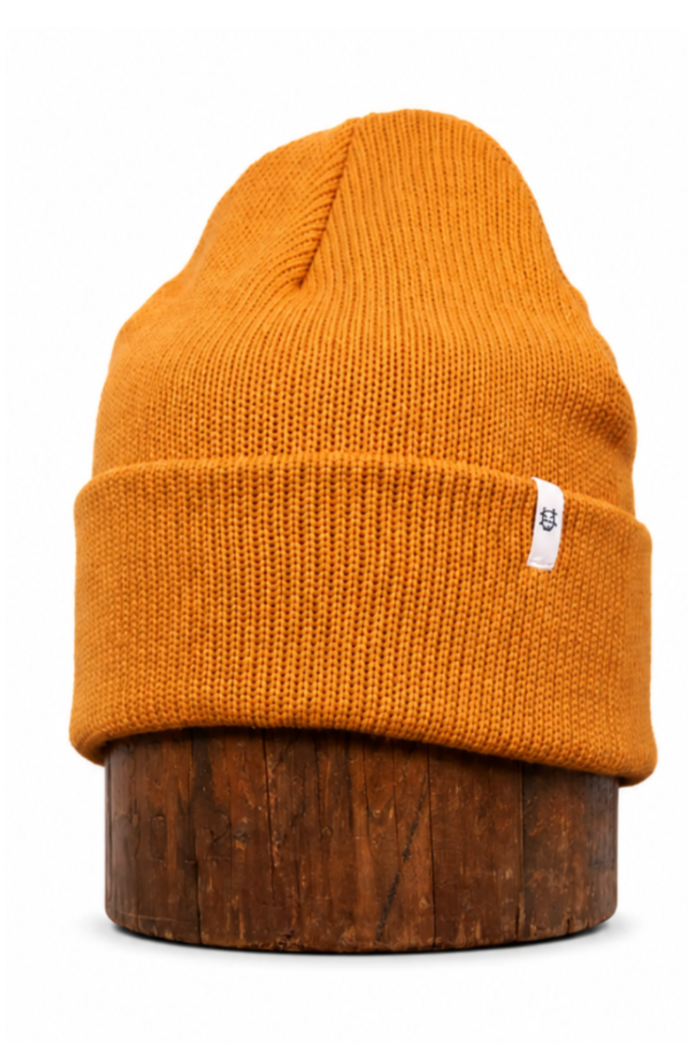 A mustard yellow knit beanie hat displayed on a dark brown wooden stand against a plain white background.