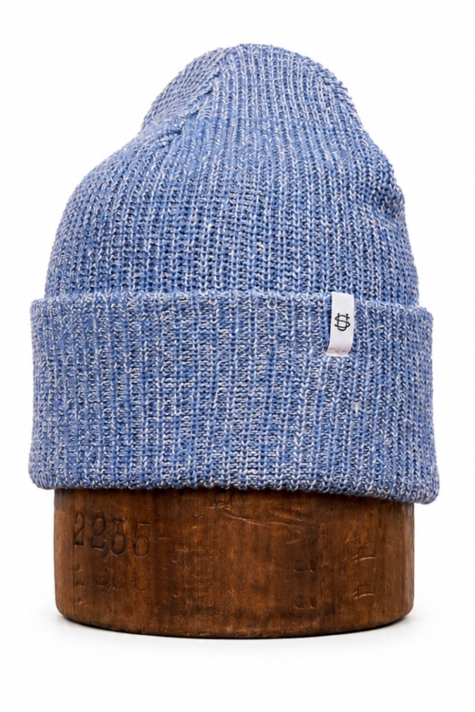 A blue heathered ribbed knit beanie hat displayed on a wooden stand against a plain white background.