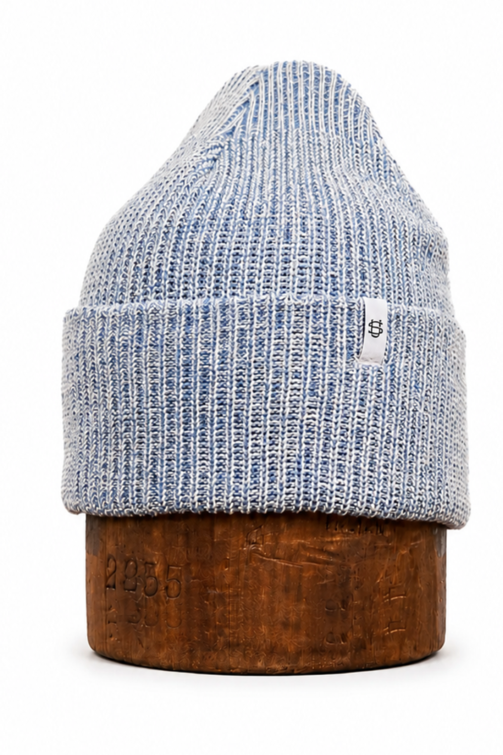 A light blue and white heathered knit beanie hat displayed on a round wooden stand against a plain white background.