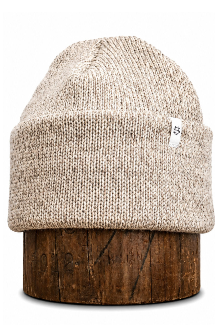 A beige knit beanie hat displayed on a dark brown wooden stand against a plain white background.