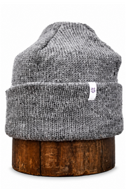 A gray heathered knit beanie hat displayed on a round wooden stand against a plain white background.