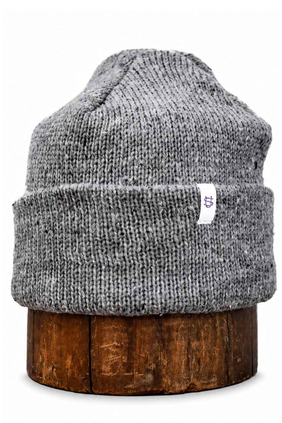 A gray heathered knit beanie hat displayed on a round wooden stand against a plain white background.