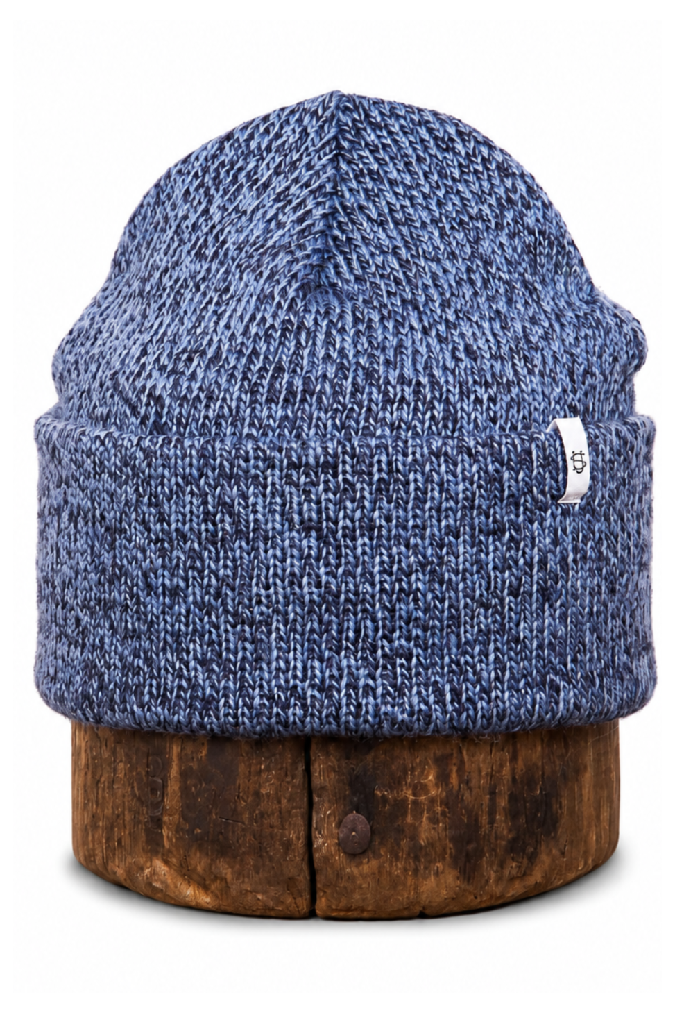 A blue marled knit beanie hat displayed on a round wooden stand against a plain white background.