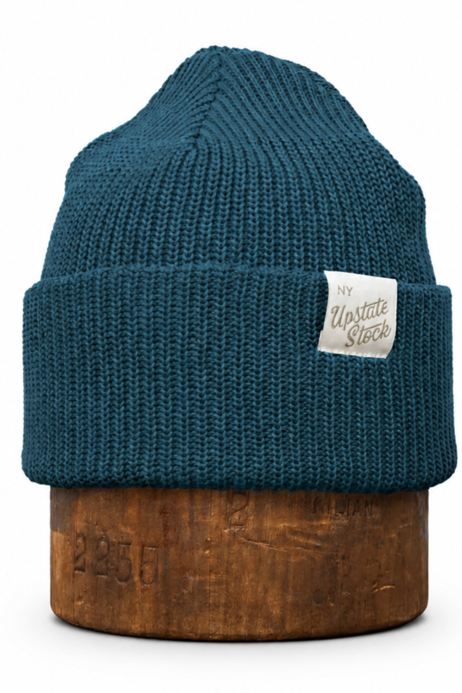 A dark teal ribbed knit beanie hat with a small white sewn-on label reading 'Vintage Vibes', displayed on a brown wooden stand against a plain white background.