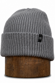 A gray ribbed knit beanie hat displayed on a brown wooden stand against a plain white background.