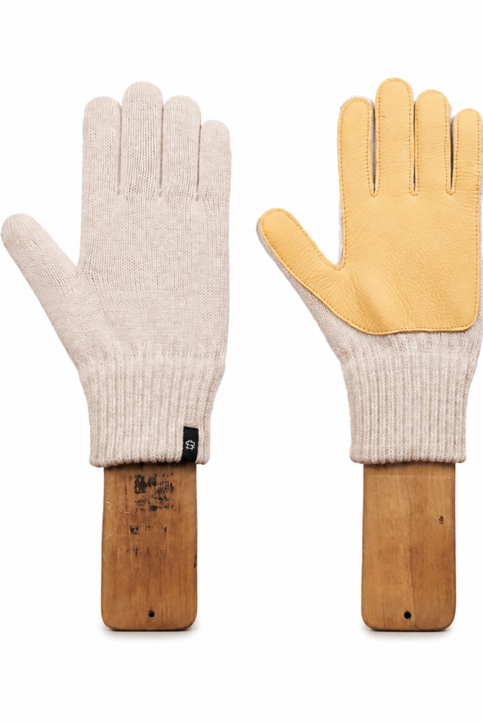 A pair of knit work gloves displayed side by side on wooden stands against a white background. One glove is shown palm-side in a light cream color, and the other is shown back-side with a contrasting light tan leather palm and ribbed cream knit cuff.