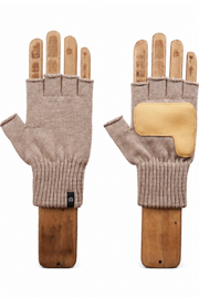 A pair of beige fingerless knit gloves displayed on wooden mannequin hands against a solid white background. One glove is shown palm-side with a small black brand tag, and the other is shown back-side featuring a contrasting light tan leather patch on the back of the hand.