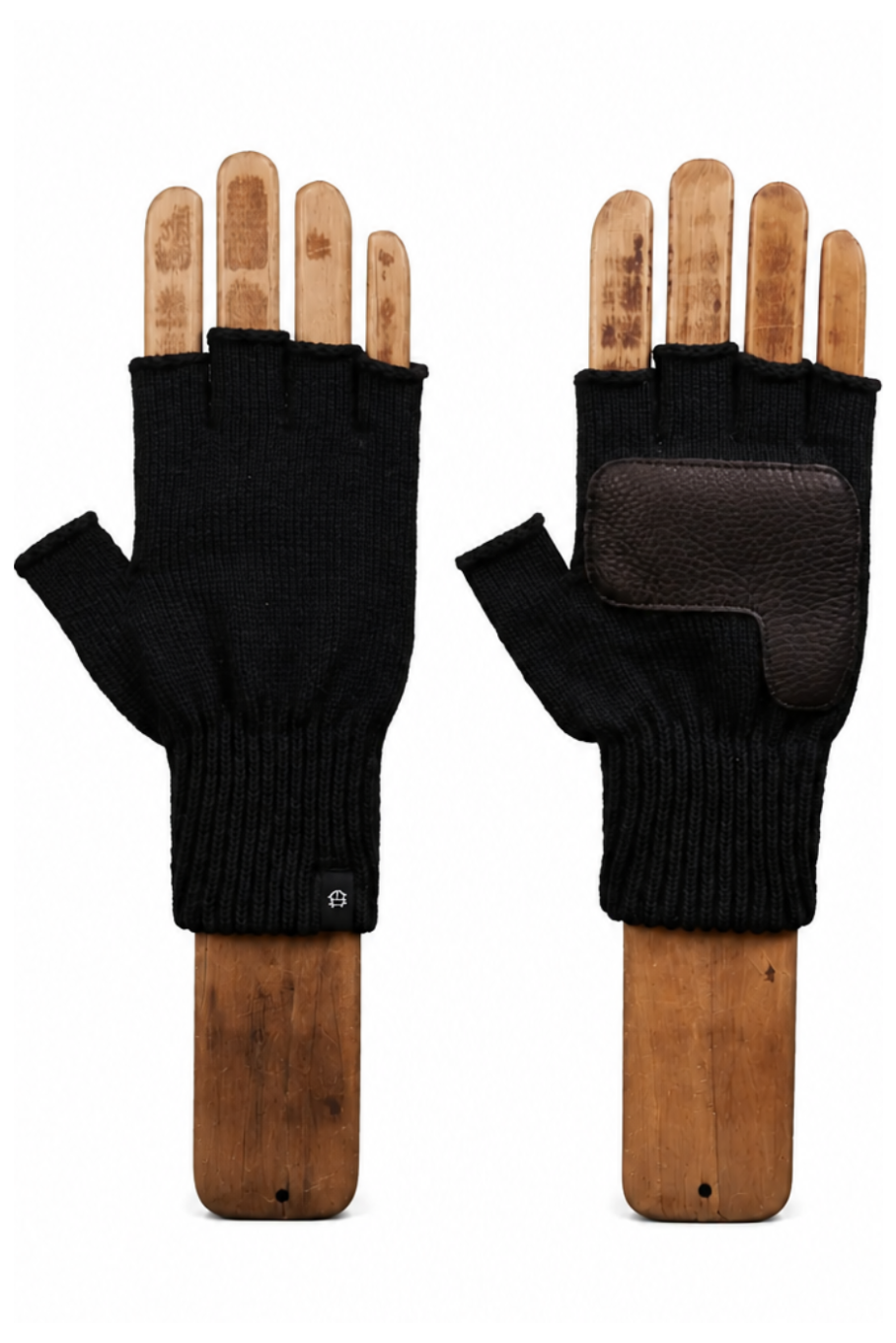 A pair of black fingerless knit gloves with brown leather palm patches, displayed on wooden hand forms against a white background.