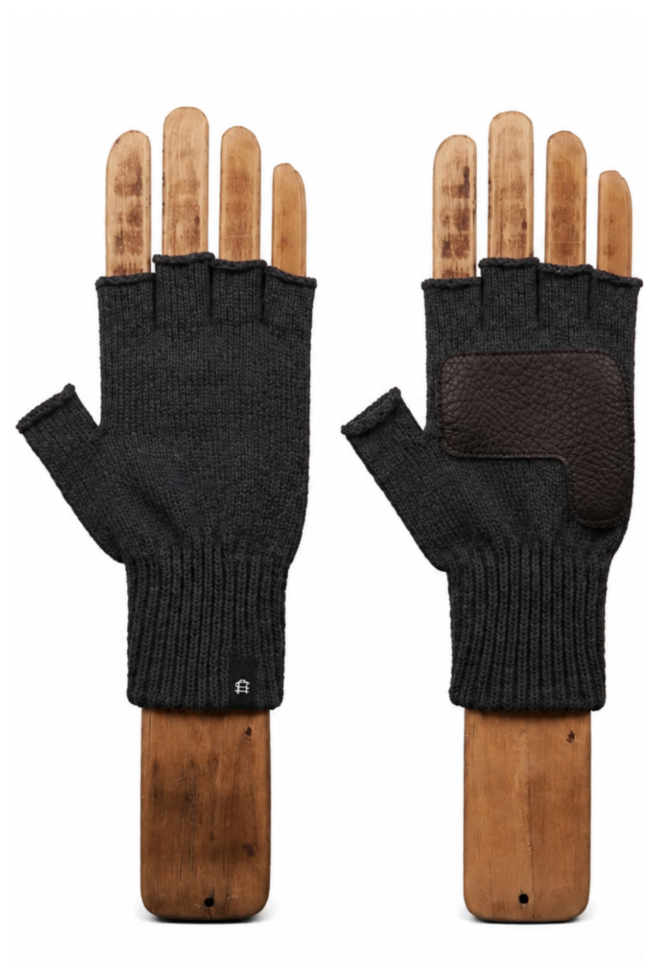 A pair of black fingerless knit gloves displayed on wooden hand forms against a plain white background, showing both the knit exterior and a textured brown palm patch.