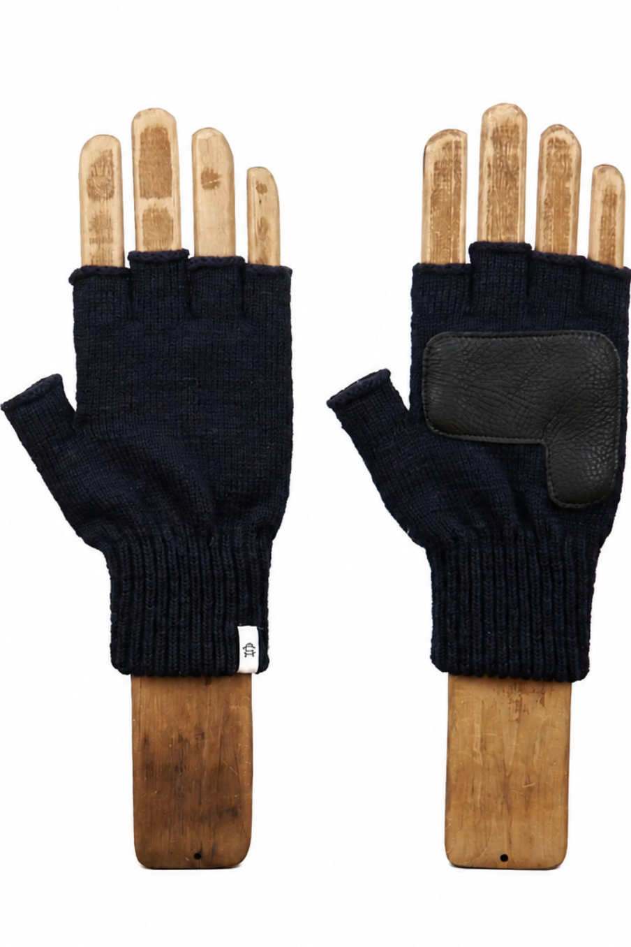 A pair of dark navy blue fingerless knit gloves displayed on wooden hand mannequins against a plain white background. One glove is shown from the back, featuring a black textured grip pad on the back of the hand.