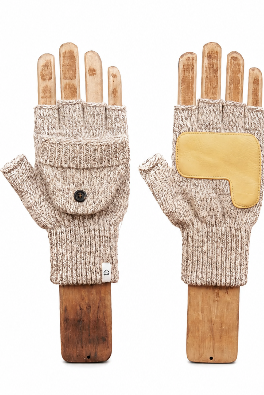 A pair of beige knit fingerless gloves displayed on wooden hand forms against a plain white background. One glove shows a front flap pocket with a small black button, and the other shows a yellow protective patch on the back of the hand.