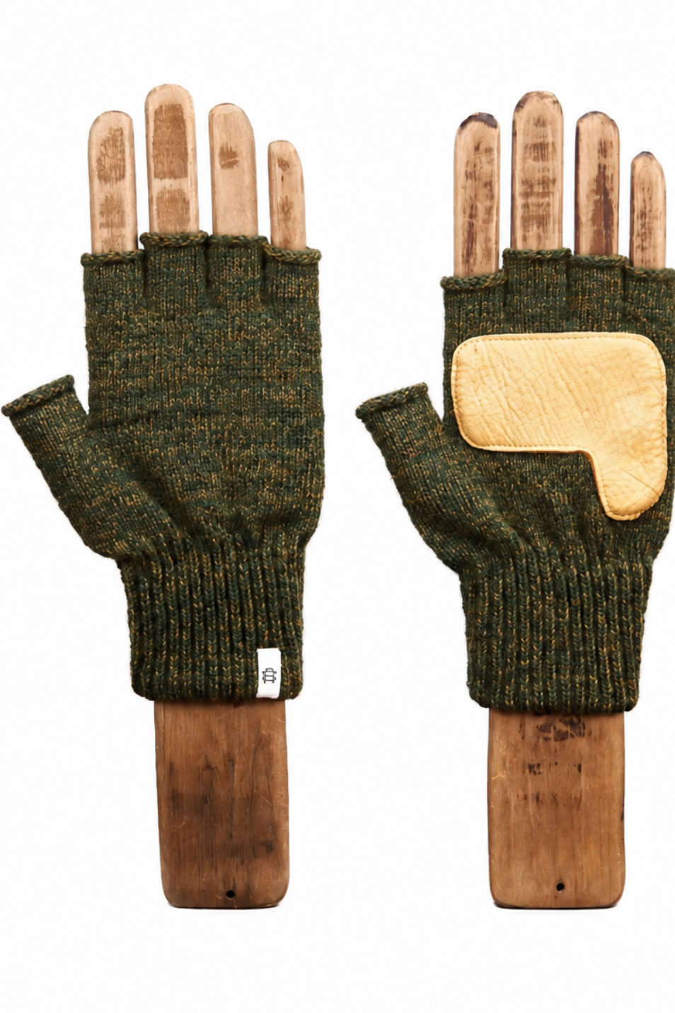 A pair of dark olive green fingerless knit gloves displayed on wooden mannequin hands against a plain white background. One glove shows the textured knit palm with a small white tag, and the other shows the back with a light tan leather patch.