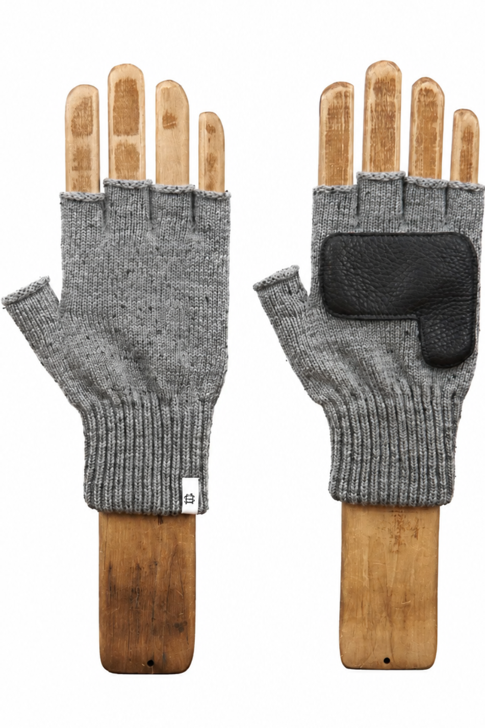 A pair of gray knit fingerless gloves displayed on wooden hand forms against a white background. The left glove is shown from the palm side, and the right glove shows the back with a black textured grip pad on the back of the hand.