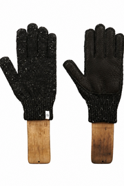 A pair of black knit gloves with textured leather palms and backs, mounted on wooden display stands against a plain white background.
