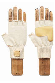 A pair of cream-colored knit fingerless gloves with tan leather patches and a small tan brand patch on the cuff, displayed on wooden hand forms against a white background.