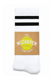 A pair of white tube socks with two black horizontal stripes near the top, wrapped in a brown paper band featuring a yellow tennis ball graphic and the text 'THE MCCARREN TUBE SOCK'.