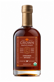 A bottle of Crown Maple Syrup, Cinnamon Infused, with amber liquid, a gold cap, and a brown label on a white background.