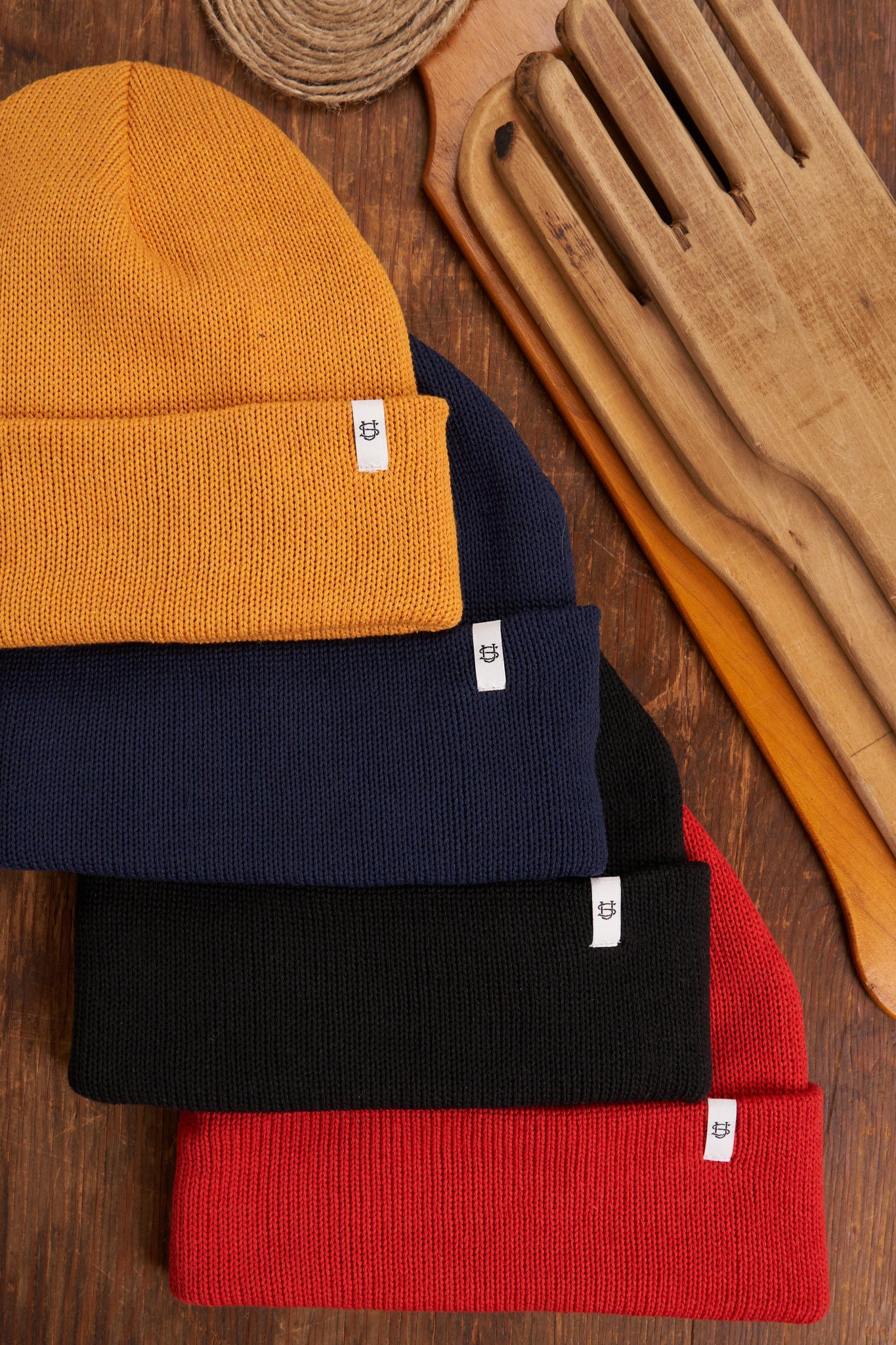 Stack of colorful knit beanie hats on a wooden surface
