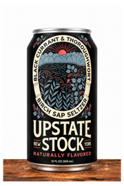 A 12 fl oz can of Upstate Stock Birch Sap Seltzer on a rustic wooden surface against a white background. The can features a black label with a detailed illustration of a forest and sun, and bold cream and red text.