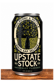 A 12 fl oz can of Upstate Stock Naturally Flavored Birch Sap Seizer beer, featuring a black label with a vintage-style illustration of a birch tree and a bird, set on a rustic wooden surface against a white background.